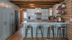 A kitchen with wooden beams, a marble island, bar stools, and built-in appliances. - Gorgeous Alpine Hollow on 3 acres - Hot Tub (Alpine)