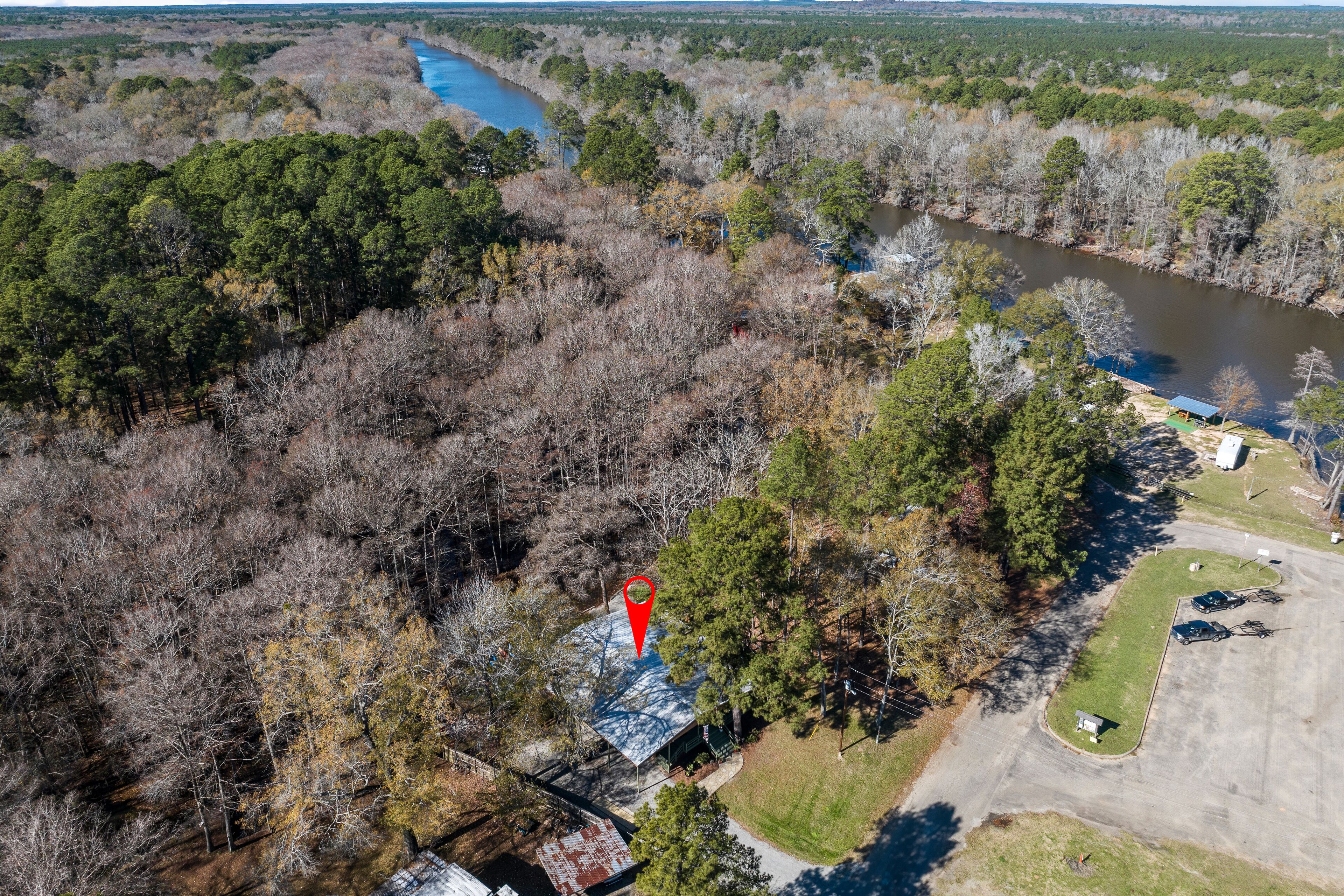 An aerial view of a property with a large open area, a river, and dense forest.