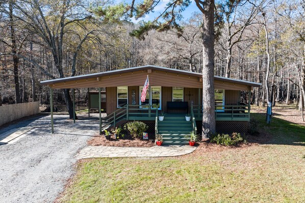 A cabin with a porch, a flag, and a stone pathway leading to it.