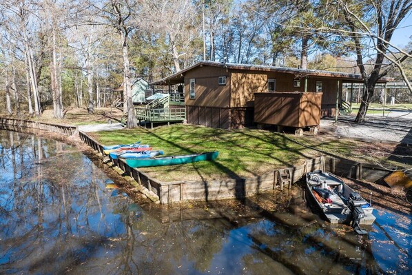 A cabin with a dock extending into a calm body of water, surrounded by trees. - Recently updated with great reviews! (Karnack)