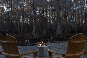 Two wooden Adirondack chairs facing a metal fire pit with two glasses of wine. - Recently updated with great reviews! (Karnack)