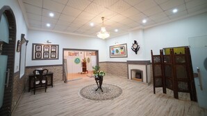 Un vestíbulo amplio con candelabro, cuadros enmarcados, chimenea y un mostrador de recepción.