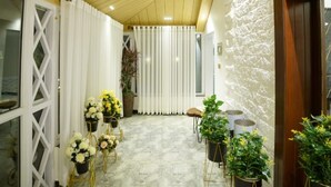 Un pasillo con piso de mármol, cortinas blancas y plantas en macetas.