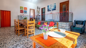 Amplia sala de estar con una mesa de comedor, sillas, un sofá y una escalera.