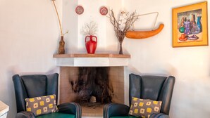 Una habitación con dos sillones de cuero, una chimenea y adornos sobre la repisa.