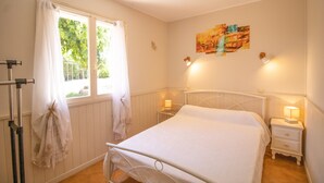 A bedroom with a bed, a window with curtains, a bedside table with a lamp, and a wall-mounted artwork. - Holiday Home 'Isula Paradise' with Mountain View, Private Terrace (LINGUIZZETTA)