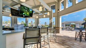 An outdoor bar area with a TV screen, chairs, and a view of the resort. - Modern 4BR Townhome with Private Pool for 10 (Kissimmee)