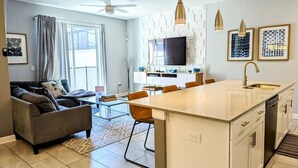 A modern apartment with a living room, dining area, kitchen, and a large island. - Modern 4BR Townhome with Private Pool for 10 (Kissimmee)