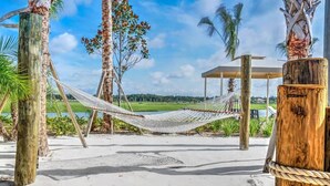 A hammock on a sandy beach with palm trees and a wooden structure in the background. - Spacious Home,Private Pool-September Special Price (Kissimmee)