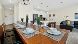 A modern dining area with a wooden table set for six, surrounded by chairs. - Spacious Home,Private Pool-September Special Price (Kissimmee)