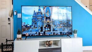 A flat-screen TV mounted on a white entertainment center with a decorative bowl and a small plant. - Mandalorian Retreat – Private Pool Near Disney (Kissimmee)