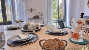 A dining table set with plates, glasses, and bread, with a view of the outdoors.