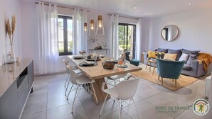 A modern dining area with a wooden table, white chairs, and pendant lighting.
