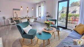 A modern living room with a dining area, a sofa, a coffee table, and a view of the outside.