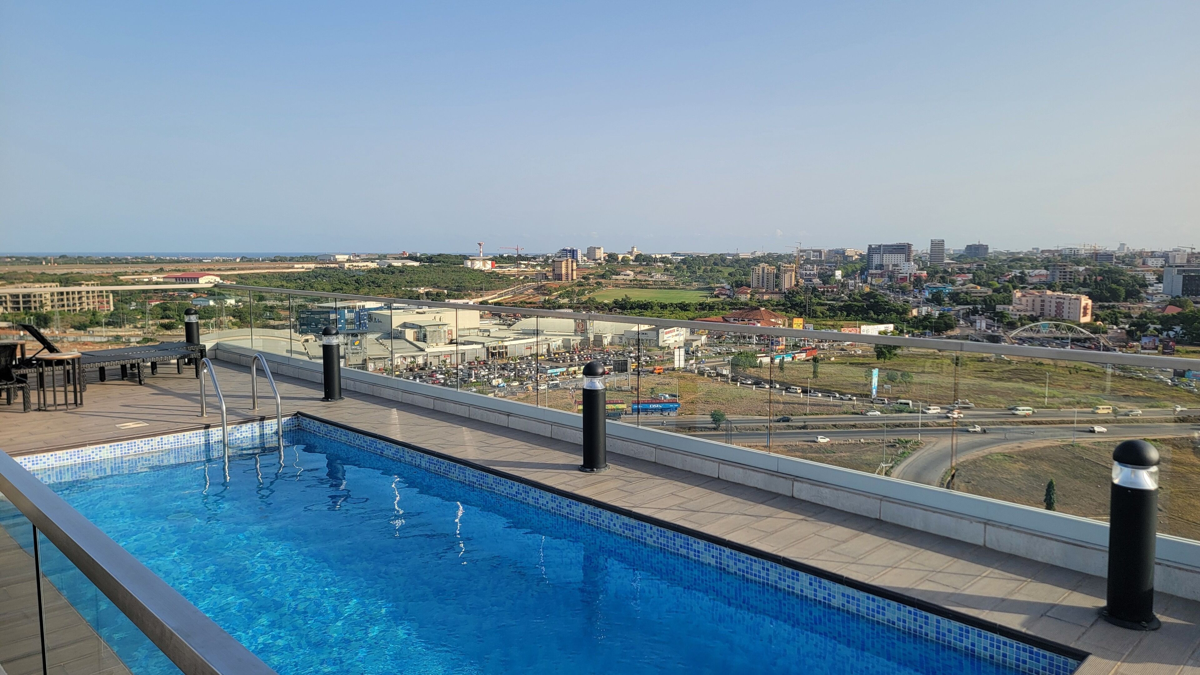Una piscina en la azotea con vistas a la ciudad, incluyendo una autopista y edificios.