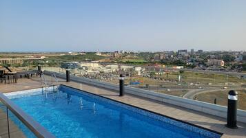 Una piscina en la azotea con vistas a la ciudad, incluyendo una autopista y edificios.