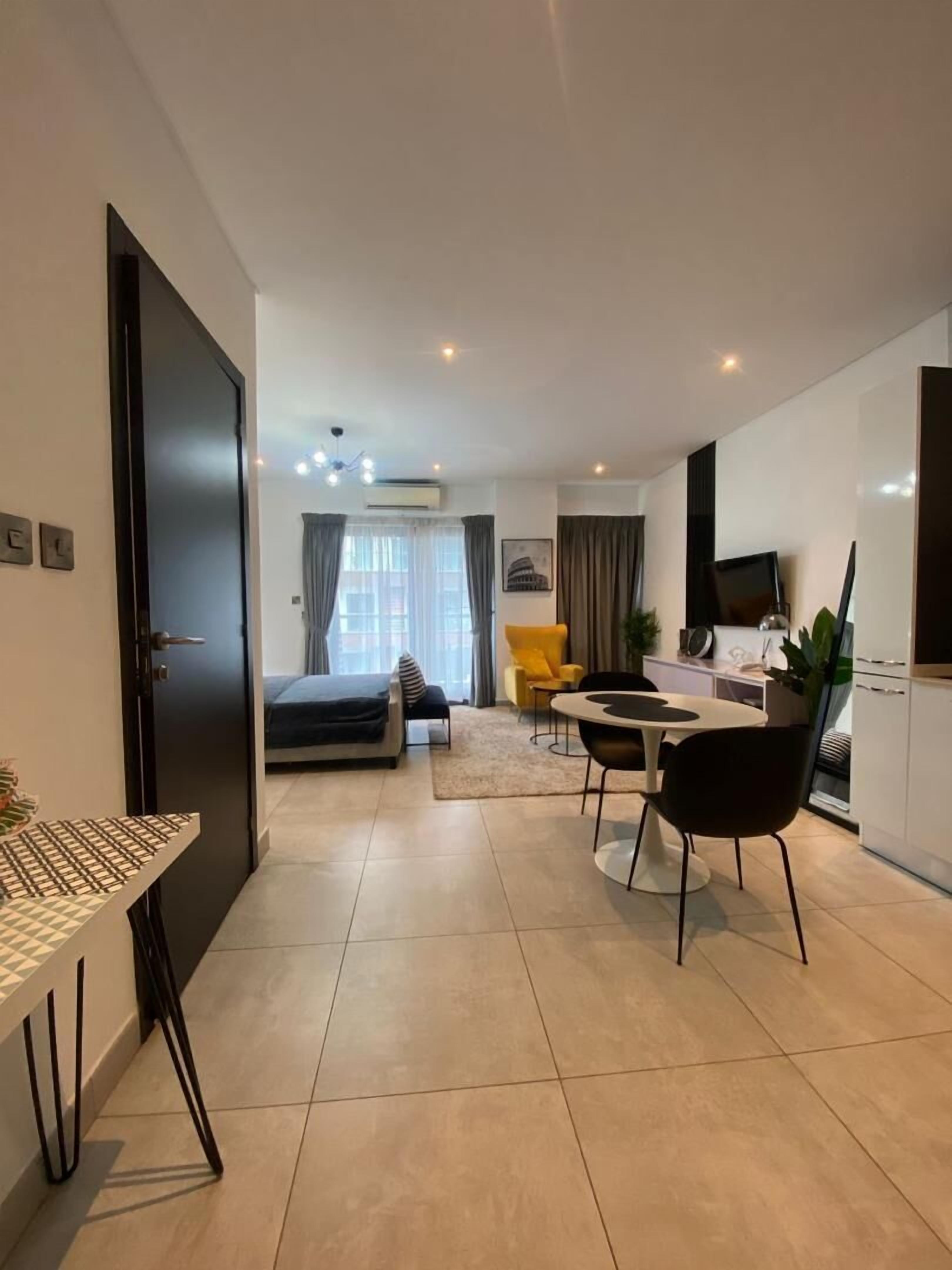 Una habitación de hotel moderna con cama, escritorio, silla, sofá y mesa de comedor.