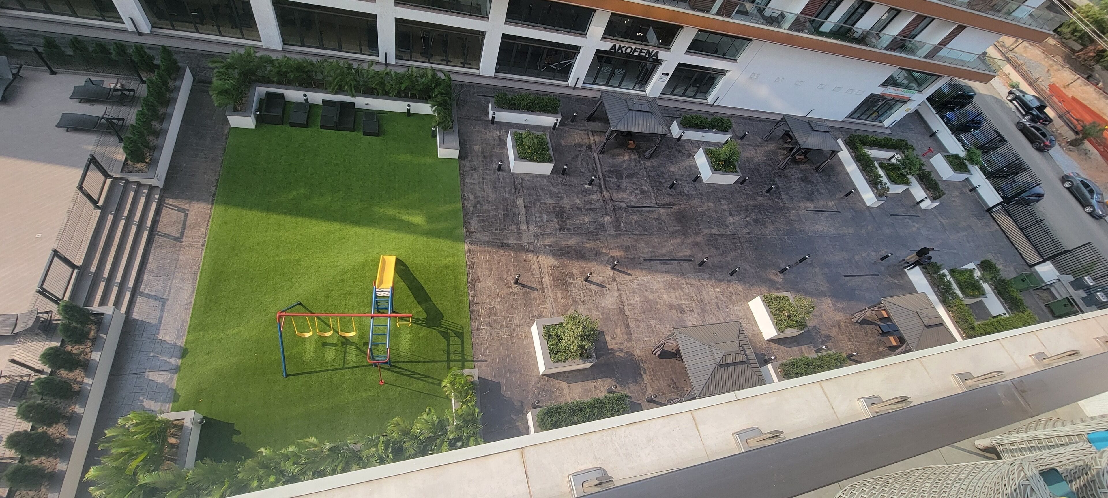 An aerial view of a modern building with a courtyard featuring a playground, seating areas, and a parking lot.
