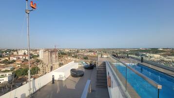 A rooftop pool with a clear view of the cityscape, including buildings and construction sites.