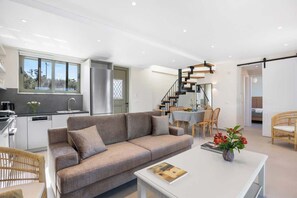A modern living room with a sofa, coffee table, and dining area.