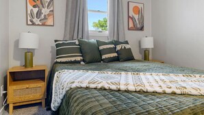 A bedroom with a bed, two bedside tables, a window with curtains, and two wall-mounted paintings. - Home located close to Downtown (Spearfish)