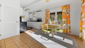 A compact kitchen with white cabinets, a dining area with a table and chairs, and a patterned curtain. - Home located close to Downtown (Spearfish)