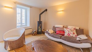 Un salón acogedor con un sofá, una silla, una mesa de centro de madera, una chimenea y un ventanal grande.
