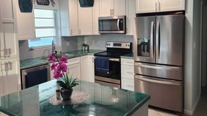 A modern kitchen with white cabinets, stainless steel appliances, a glass island, and pendant lighting. - Christmas in the FL Keys!!! Stunning sunsets, beaches 10 min away, Fishing!!! (Big Pine Key)