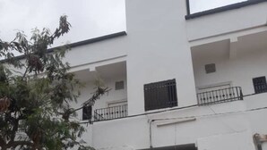 A white building with multiple balconies and a tree in the foreground. - Résidence Mouna (Nouadhibou)
