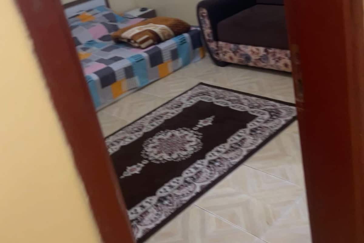 Une pièce comprenant un lit, un canapé, une fenêtre et un tapis à motifs.