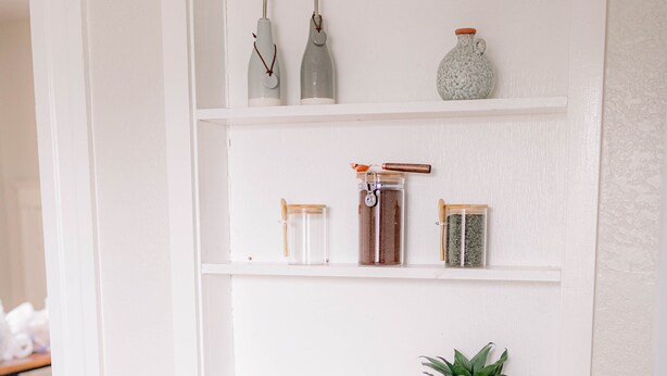 A white wooden console table with shelves, a drawer, and a small plant.