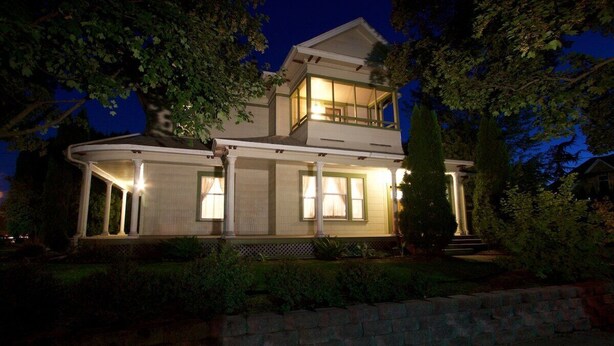 A two-story house with a balcony, large windows, and a well-lit front porch. - Large & spacious: 12 guests & walkable to Main St! (Walla Walla)