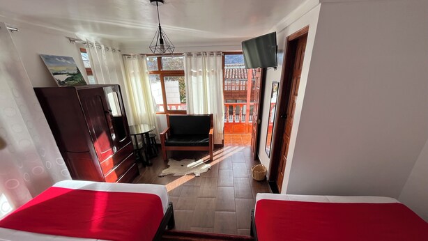 Habitación de hotel con dos camas, televisión, escritorio y una silla.