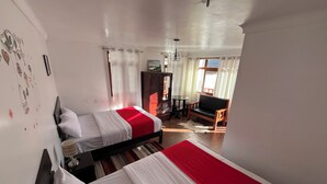 Una habitación con dos camas, un armario de madera, una mesita y una silla.
