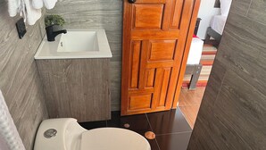 Un baño con un inodoro blanco, un lavabo con grifo negro y una puerta de madera.