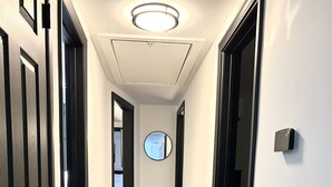 A hallway with dark wooden flooring, white walls, and a light-colored rug. - Hot Tub & Cloud Ceiling House (Montville)