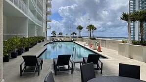 Un espace piscine avec des chaises longues et vue sur l’océan.