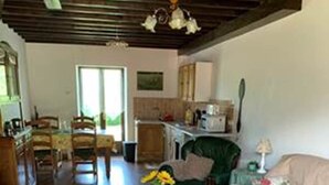 A cozy living room with a green sofa, a wooden coffee table, and a dining area with chairs and a table. - Sunrise - A beautiful 2 bedroom Gite in the unspoiled countryside of the Cruese (CHENIERS)