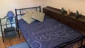 A small bedroom with a single bed, a nightstand, a lamp, and two wall-mounted pictures. - Sunrise - A beautiful 2 bedroom Gite in the unspoiled countryside of the Cruese (CHENIERS)