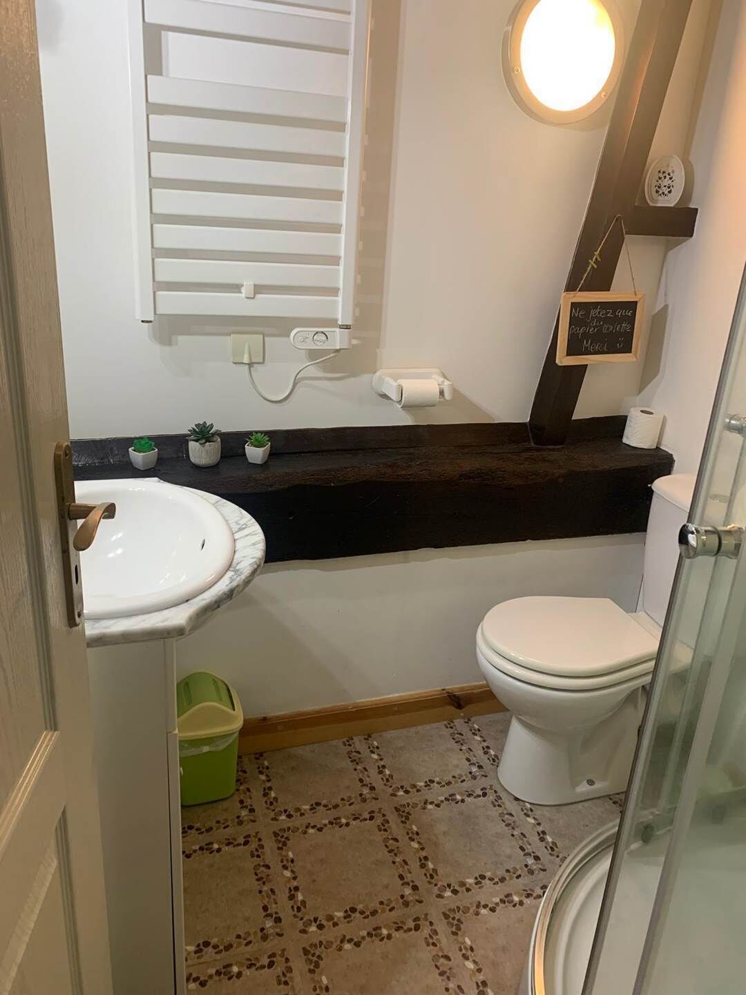 A compact bathroom with a white sink, a toilet, and a small green trash bin.