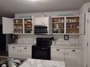 Uma cozinha com armários brancos, fogão preto e micro-ondas.