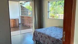 Un dormitorio con cama, ventana, balcón y ventilador de techo.