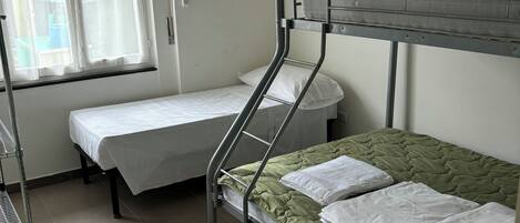 Dormitorio con literas, ventana, mesita de noche y lámpara colgante.