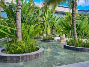 Surrounded by lush tropical plants, this serene outdoor space features a peaceful water feature.