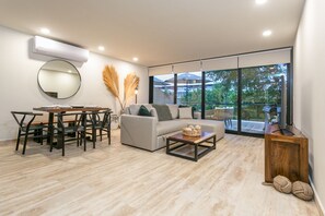 Relax in this stylish living space with a dining area, comfortable sofa, and sliding glass door leading to a serene outdoor view.