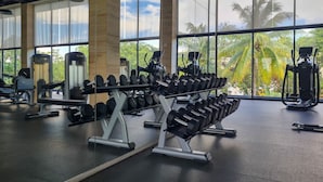 A gym with weightlifting equipment and large windows offering a view of palm trees.