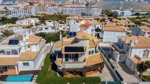 A residential area with multiple buildings, a swimming pool, and a large hotel in the background. - Monteiro V4 - VIP Properties by Interhome (Albufeira)