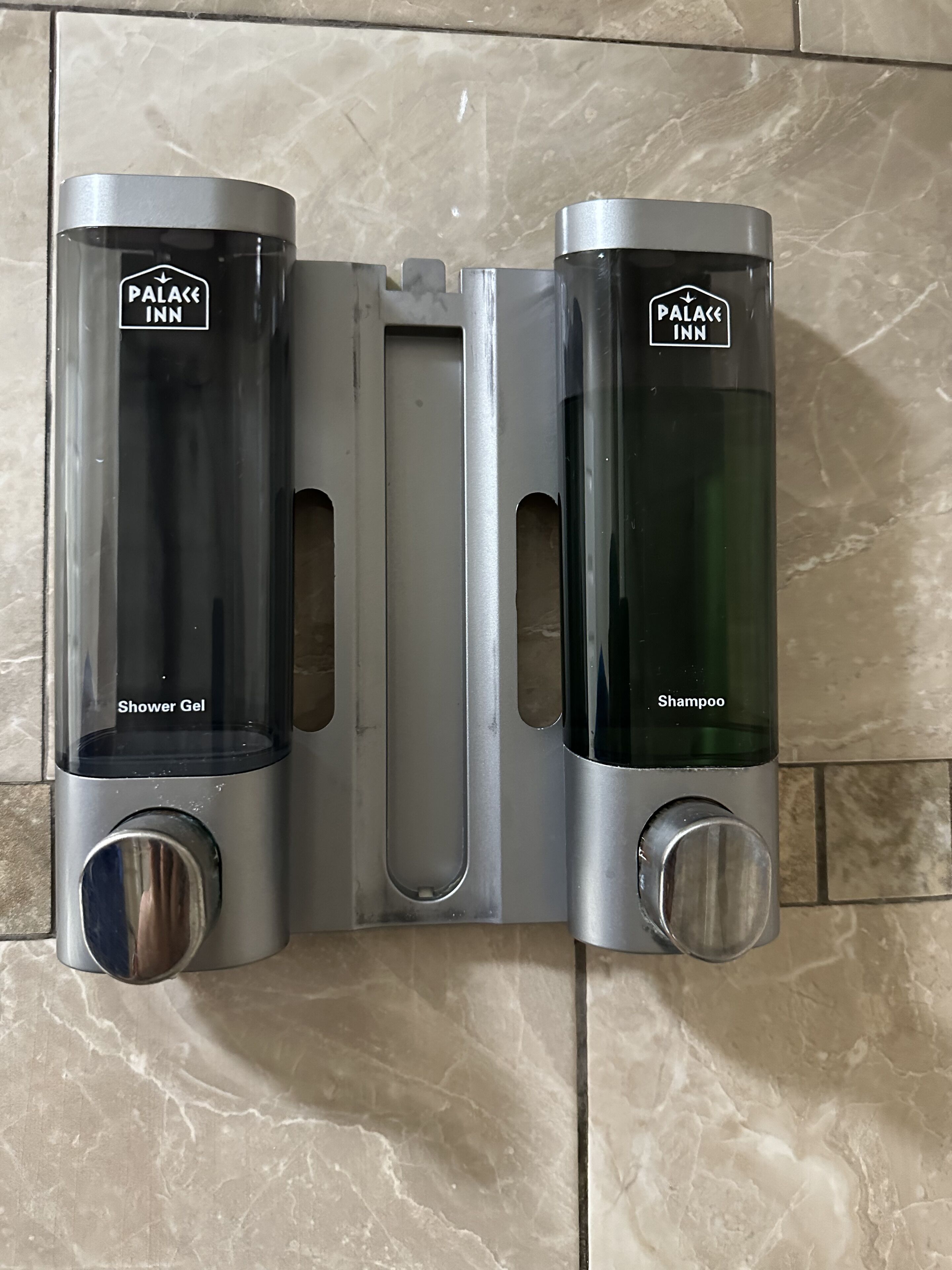 Une salle de bain avec un distributeur de gel douche et un distributeur de shampoing fixés au mur.