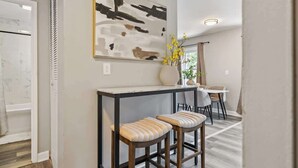 Eine moderne Küche mit Marmorarbeitsplatte, einem schwarz-weißen abstrakten Gemälde und einer Vase mit gelben Blumen.