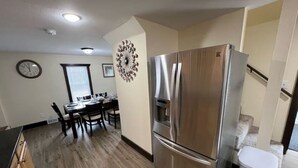 Une cuisine moderne avec un réfrigérateur en acier inoxydable, une table à manger en bois et des chaises.